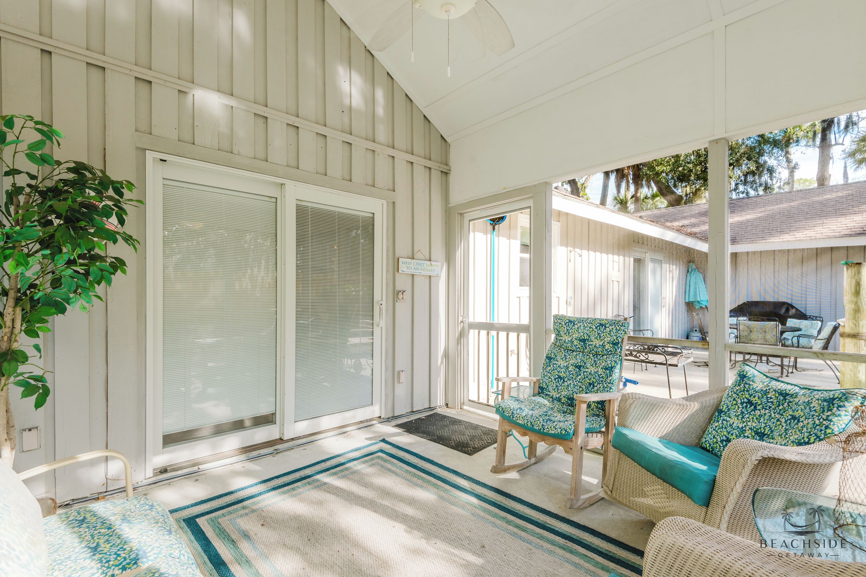 A covered porch with wicker furniture, a sliding glass door, and a view of the backyard.