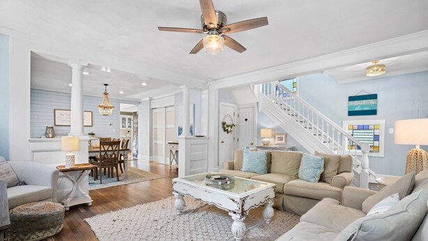A spacious living room with a white coffee table, beige sofas, and a staircase leading to another level. - Peach Perfect Victorian Home with Gourmet Kitchen (Cape Charles)