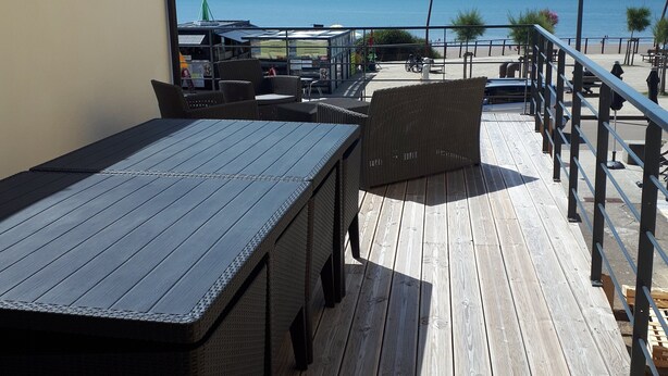 Eine Holzterrasse mit Sitzgelegenheiten, Geländer und Meerblick.
