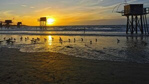 Ein Strand bei Sonnenuntergang mit einem Rettungsturm und einer Pier.