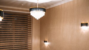 A staircase with a black railing, a chandelier, and wall sconces. - The Clocktower Hotel (Baku)