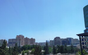 A cityscape with multiple high-rise buildings, including a prominent hotel with a modern design and a view of the surrounding urban area. - The Clocktower Hotel (Baku)