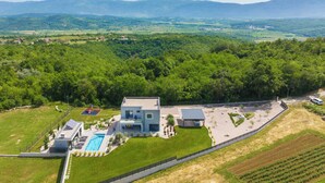A modern two-story house with a swimming pool, surrounded by lush greenery and mountains in the background. - Villa Tia in Kukurini  - Haus für 8 Personen (Pican)