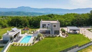 A modern two-story house with a swimming pool, a covered outdoor seating area, and a view of distant mountains. - Villa Tia in Kukurini  - Haus für 8 Personen (Pican)
