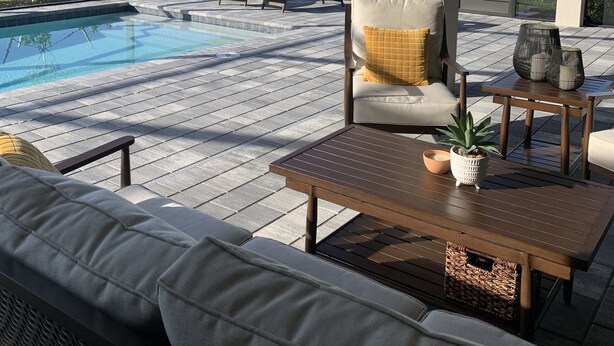 Un espace extérieur abrité comprenant une piscine, des chaises longues et une table en bois.
