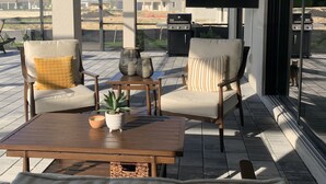 Un patio abrité comprenant deux chaises, une table basse et un téléviseur.