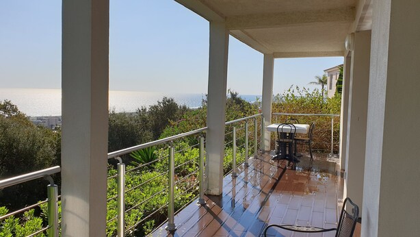 Un balcón con vistas al mar, una mesa y sillas.