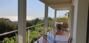 Un balcón con vistas al mar, una mesa y sillas.