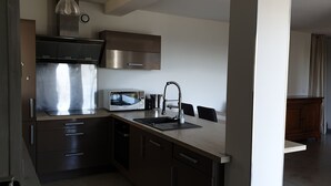 Una cocina moderna con electrodomésticos de acero inoxidable, un lavamanos y un comedor con una mesa y sillas de madera.