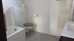 Un baño pequeño con inodoro, lavabo y zona de ducha.