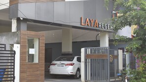 En grind leder in till en byggnad där det finns en skylt med texten ”LAYAREGEMS”.