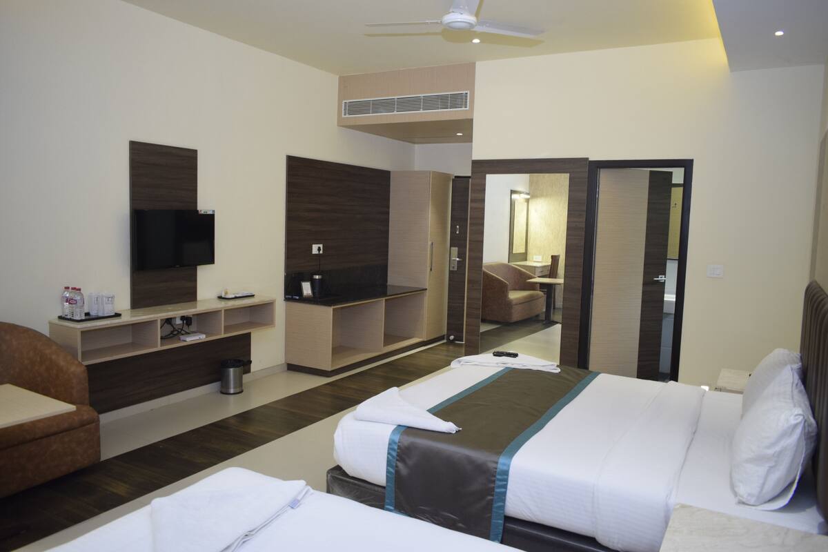 A hotel room with a bed, a TV, a desk, and a mirror.