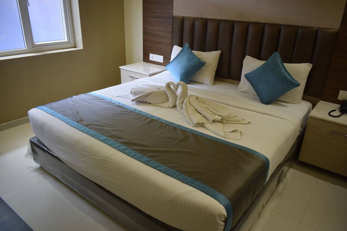 A neatly made bed with a blue accent, a wooden headboard, and a bedside table with a phone.