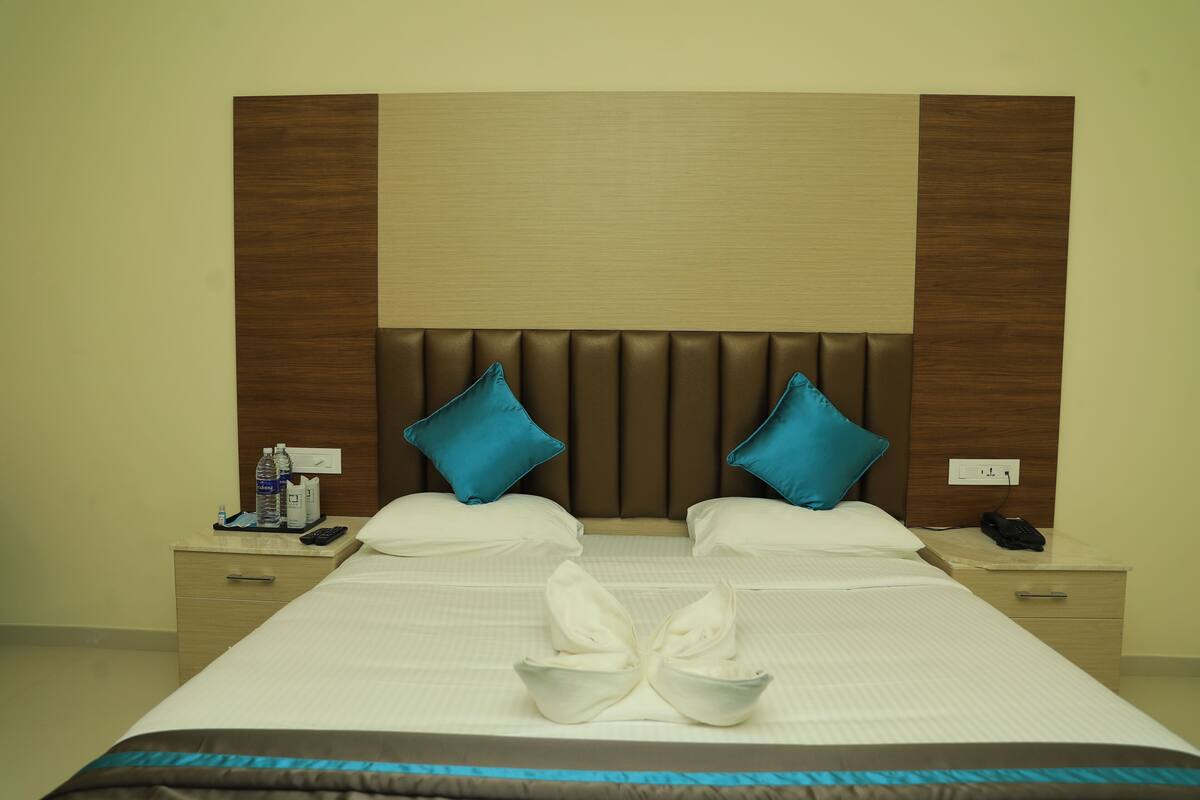 A hotel room with a large bed, two nightstands, a wooden headboard, and a blue pillow.