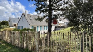 Ein Wohngebiet mit einem Haus, das ein geneigtes Dach, einen Holzzaun und einen Baum hat.