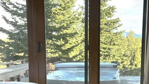 A bedroom with a large sliding glass door leading to a hot tub area.