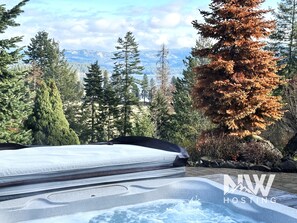 A hot tub in a forested area with a view of mountains. - Luxury Home—Fireplaces, Hot Tub, Fire Pit, Soaking Tub & Stunning Views for Ultimate Relaxation! (Hayden)