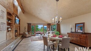 A spacious living room with a fireplace, a dining area with a chandelier, and a view of the outdoors.