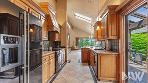 A spacious kitchen with modern appliances, wooden cabinetry, and a view of a lush garden.