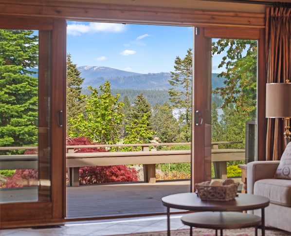 Una habitación con puerta corrediza de vidrio que da a un balcón con vistas a la montaña. Hay un sofá y una mesita con un cuenco decorativo.