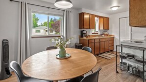Une cuisine compacte avec des meubles en bois, une table à manger avec des chaises et un four encastré.