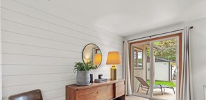 A room with a wooden dresser, a mirror, a potted plant, and a sliding glass door leading to an outdoor patio.