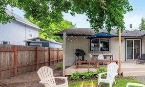A backyard with a barbecue area, outdoor seating, and a wooden fence.