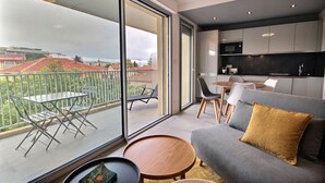 A modern living area with a sofa, a round wooden table, and a balcony with a dining set. - Large, newly renovated studio, quiet, 100 metres from the beautiful La Salis beach (Antibes)