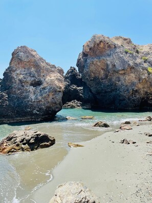 Ein felsiger Strand mit großen Steinen und klarem Wasser.