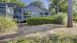 A two-story house with a covered porch, surrounded by trees and shrubs.