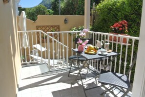 A balcony with a table, chairs, and a potted plant. - Crawford Home (Sant'Agnello)