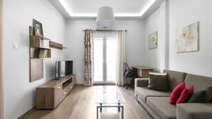 Un salon moderne comprenant un canapé, une table basse, un téléviseur et un bureau avec une chaise.