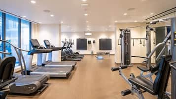 Un gimnasio moderno con cintas de correr, elípticas y equipo de levantamiento de pesas.