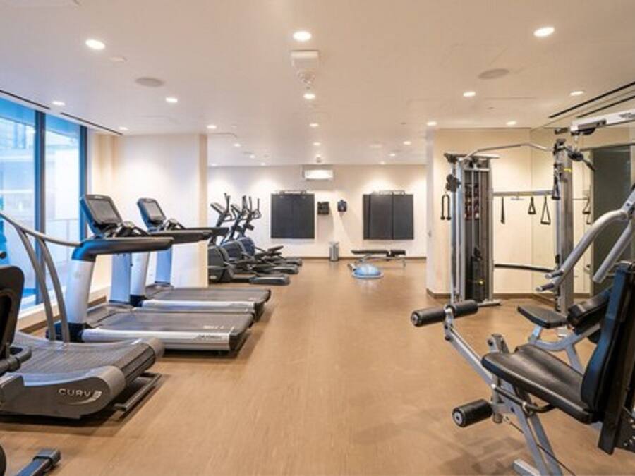 Un gimnasio moderno con cintas de correr, elípticas y equipo de levantamiento de pesas.
