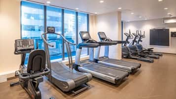 Un gimnasio con cintas de correr, elípticas y bicicletas estáticas.
