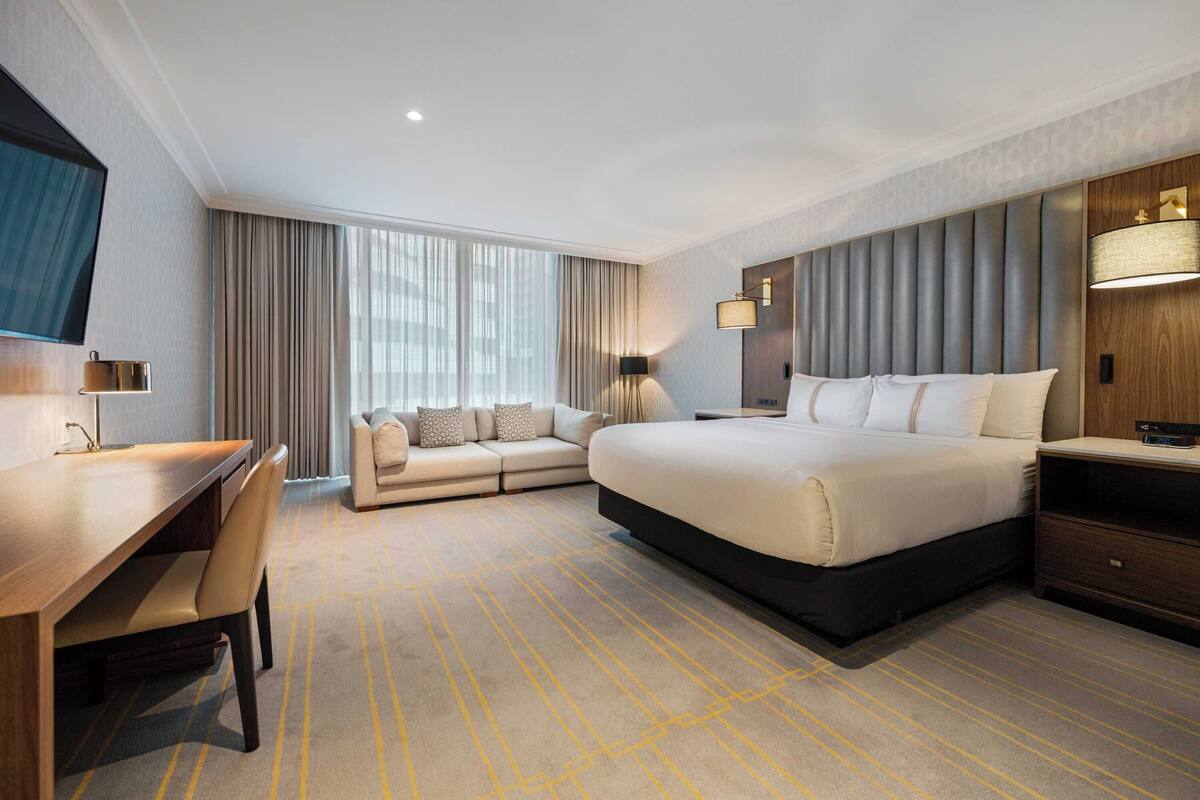 Una habitación de hotel con una cama grande, un sofá, un escritorio y un televisor.