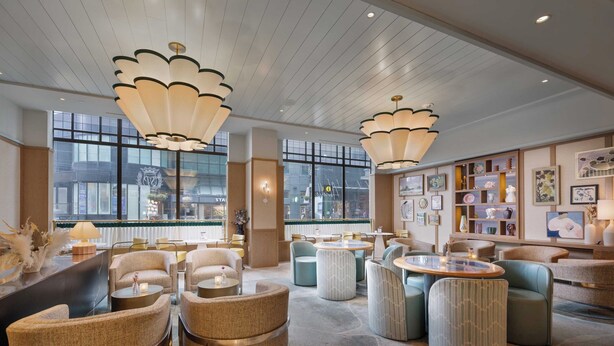 Een moderne lounge met comfortabele zitplaatsen, grote ramen en decoratieve verlichting.