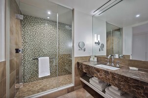 A modern bathroom with a glass-enclosed shower, a marble vanity, and a large mirror.