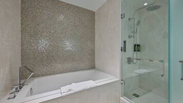 Un baño moderno con ducha de mampara de vidrio, una bañera independiente y un muro de mosaicos.