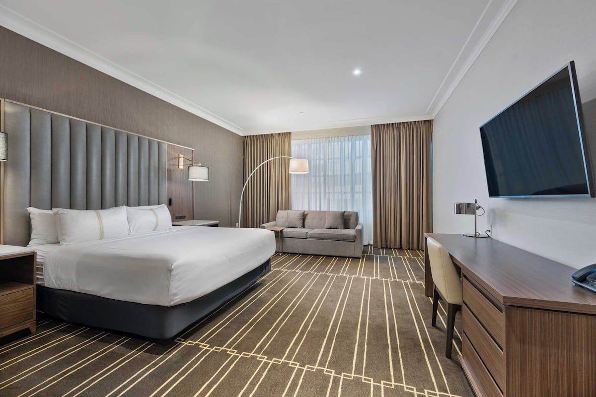 Una habitación de hotel con una cama grande, un sofá, un escritorio y un televisor.