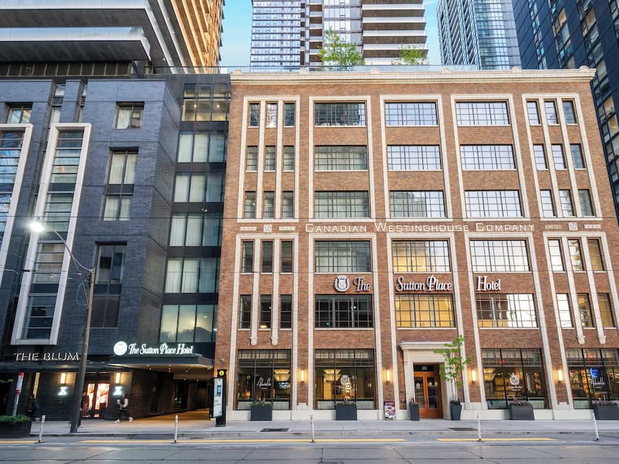 A hotel with a classic facade, featuring large windows and a prominent sign for The Sutton Place Hotel.