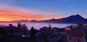 A village with traditional architecture, a prominent church, and a mountain range in the background. - Casa Giuditta, Nuovo e Indipendente Appartamento con Meravigliosa Vista Lago (Albisano di Torri del Benaco)