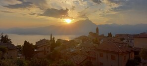 A coastal town with a prominent church and a clear view of the sea and mountains in the background. - Casa Giuditta, Nuovo e Indipendente Appartamento con Meravigliosa Vista Lago (Albisano di Torri del Benaco)