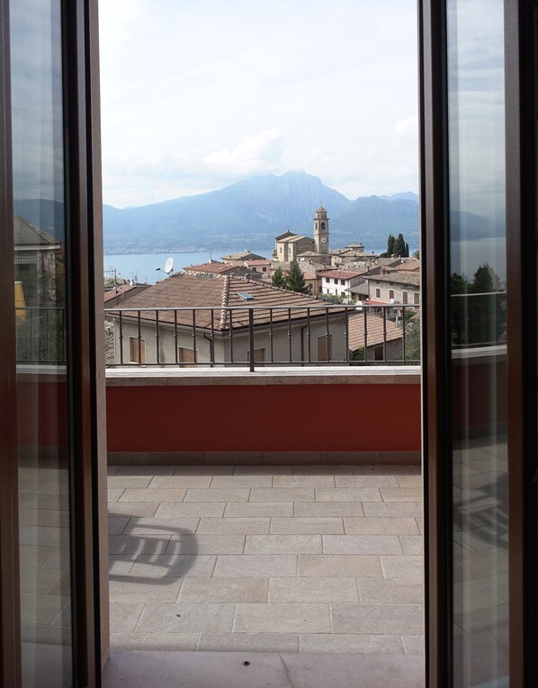 A balcony with a view of a town, a lake, and mountains. - Casa Giuditta, Nuovo e Indipendente Appartamento con Meravigliosa Vista Lago (Albisano di Torri del Benaco)
