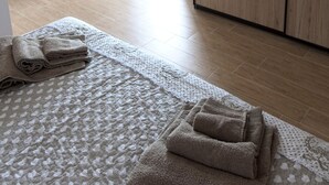 Una camera da letto con un armadio in legno, un letto con copripiumino decorato e vista all'esterno attraverso una porta aperta.
