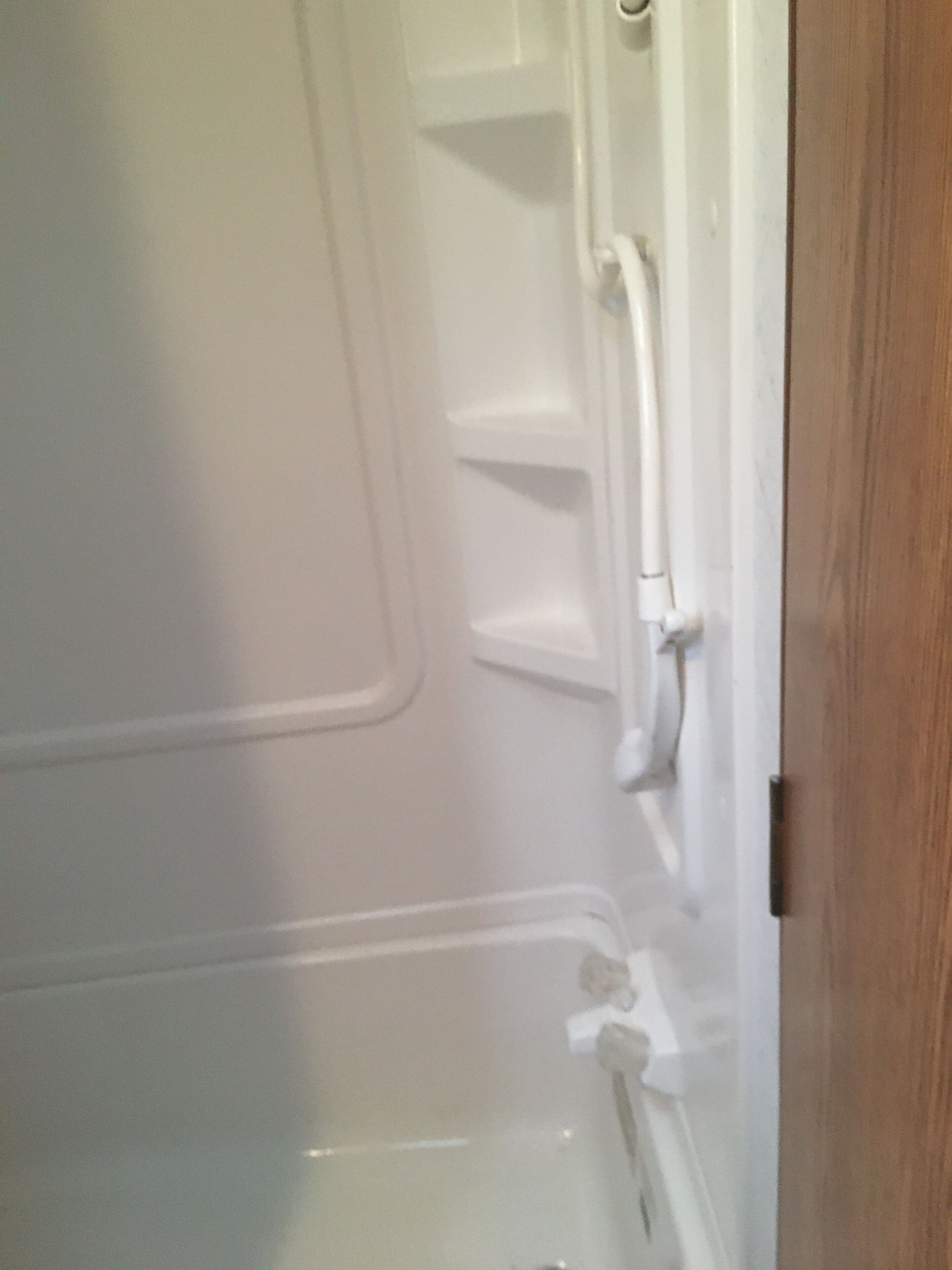 Un baño con una bañera blanca, una puerta de madera y un perchero blanco.