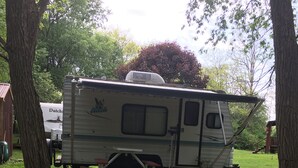 Ein Wohnmobil auf einer Wiese mit Picknicktisch und Feuerstelle.