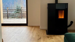 A room with a wooden floor, a black fireplace, and a large window with a mountain view. - 🏔 Symphonie des Cimes - fully renovated 2024 | Rando & Tennis  (Passy)