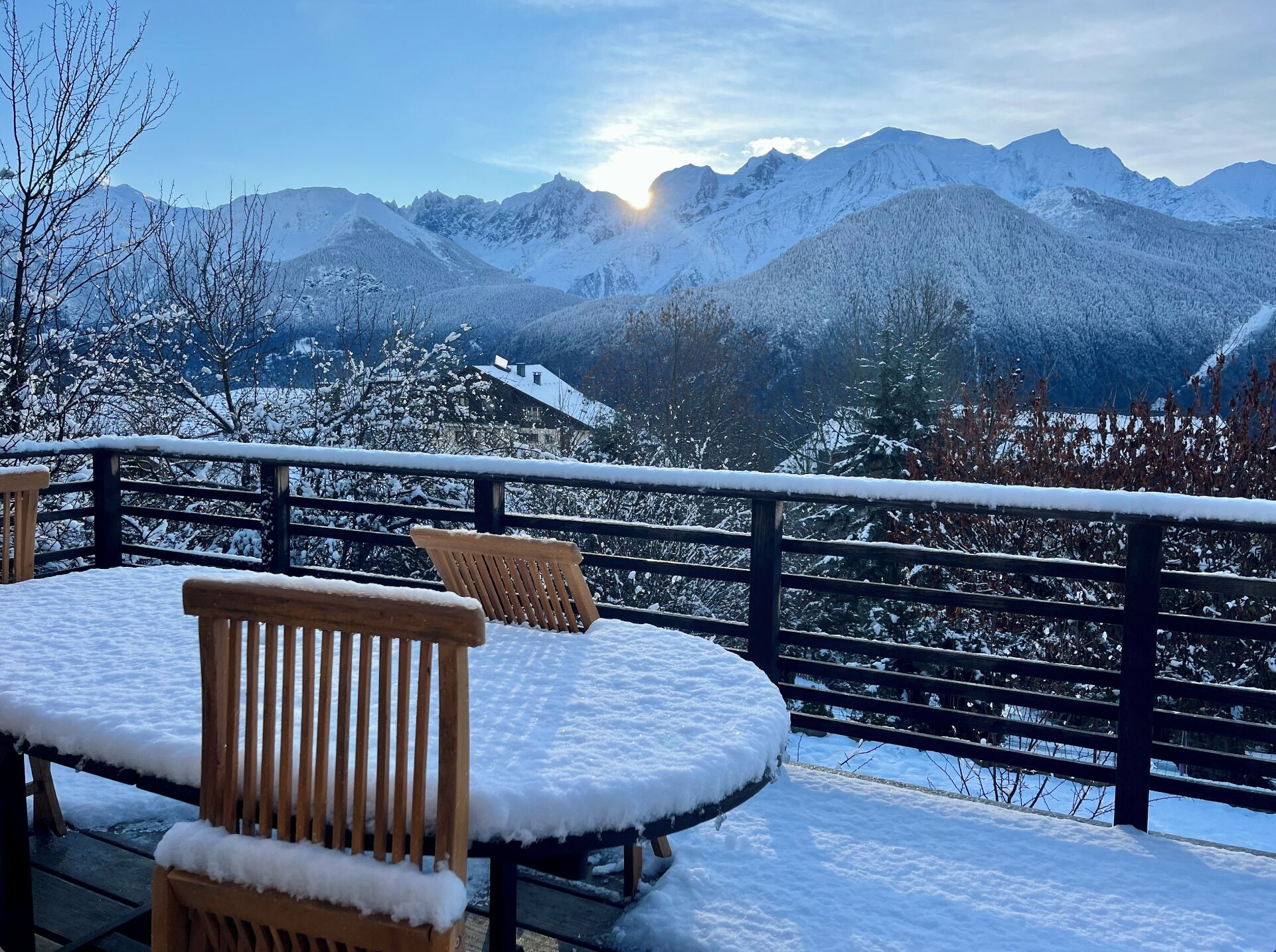Un espace extérieur aménagé avec des sièges, recouvert de neige, et offrant une vue sur des montagnes enneigées.