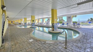 An indoor swimming pool with a tiled floor, yellow pillars, and a view of the ocean. - Camelot By the Sea 1111 - Remodeled Spring 2023 - 2 Bed/2 Bath (Myrtle Beach)